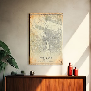 May include: A vintage-style map print of Portland, Oregon. The map is printed on a textured paper with a faded, aged look. The map shows the city streets and landmarks. The text "PORTLAND OREGON 45.5122° N | 122.6587° W" is printed at the bottom of the map.