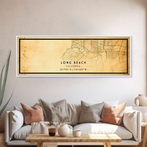 May include: A vintage-style map print of Long Beach, California, with a faded yellow background and black lines depicting streets and waterways. The text "LONG BEACH CALIFORNIA 33.7701' N | 118.1937' W" is printed in black at the bottom of the map.