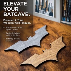 Op de afbeelding: Twee houten Batman logo wandplaten in grijze en houtnerf afwerkingen. De platen zijn precisie gesneden uit gelaagd hout en kunnen direct aan muren worden bevestigd. De tekst "ELEVATE YOUR BATCAVE" is ook inbegrepen.