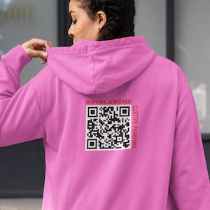 Op de afbeelding: Een roze hoodie met een zwart-witte QR-code en de tekst "ROYALARCH5 CUSTOM PRINTING" op de rug.