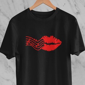 May include: Black t-shirt with a red graphic of a pair of lips with musical notes coming out of them.