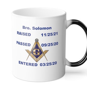 May include: White ceramic coffee mug with a black handle. The mug has a black and gold Masonic symbol with the letter G in the center. The text on the mug reads "Bro. Solomon RAISED 11/25/21 PASSED 09/25/20 ENTERED 03/25/20".