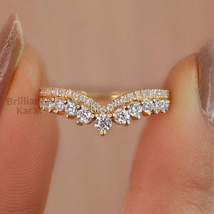 Puede incluir: Un anillo de oro con un diseño en forma de V engastado con pequeños diamantes redondos.