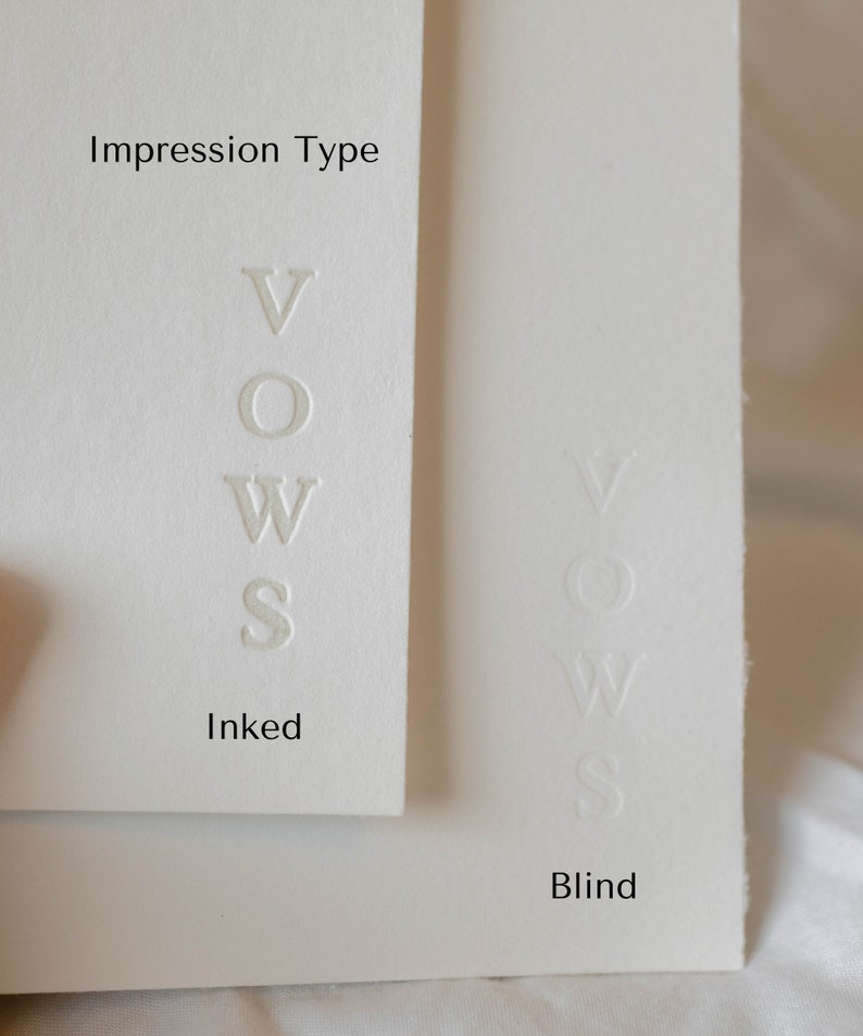 May include: Close-up of two white cards with the word "VOWS" embossed in different ways. The card on the left has the word "VOWS" embossed in ink, while the card on the right has the word "VOWS" embossed in blind. The card on the left is labeled "Inked" and the card on the right is labeled "Blind".