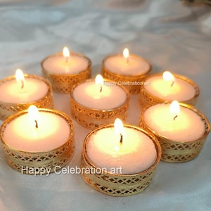 以下が含まれることがあります： 白いろうそくが燃えている、金色のティーライトキャンドルホルダーが8つあります。キャンドルホルダーは、装飾的で複雑なデザインをしています。