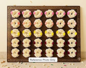 May include: A rectangular dark wood board with a decorative border, featuring thirty circular white floral wreaths arranged in five rows of six. Each wreath is accented with a small colored flower in pink, peach, yellow, or deep red.