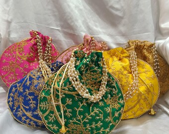 Puede incluir: Cinco bolsas redondas de cordón con bordados en varios colores, incluyendo rosa, azul, verde y amarillo. Cada bolsa tiene un diseño floral dorado y una cadena de perlas unida al cordón.