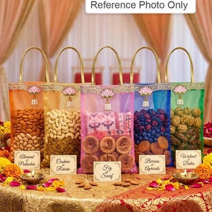 Puede incluir: Cinco bolsas de regalo decorativas llenas de nueces, frutas secas y una bufanda. Cada bolsa tiene un asa dorada y está etiquetada con el contenido: Almendras y Pistachos, Anacardos Pasas, Bufanda de Higo, Bayas y Albaricoques y Dátiles de Nuez. Las bolsas están sobre un mantel dorado.