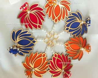 May include: Six decorative lotus flower ornaments with gold trim and colorful accents. Each ornament has a tassel hanging from the bottom. The ornaments are connected by a string of white pearls and gold rings.
