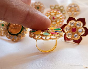 May include: A set of colorful, gold-tone, decorative rings with various designs. The rings feature a variety of gemstones, including red, green, blue, and yellow. The rings are set on a white background.