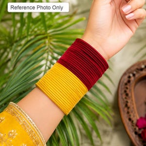 May include: A set of thin, stacked bangles featuring a vibrant yellow color on the lower half and a deep maroon color on the upper half. The bangles have a smooth, matte texture and are worn together as a wide, multi-layered wrist accessory.