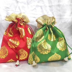 Puede incluir: Dos pequeñas bolsas de cordón con patrones dorados y rojos o dorados y verdes. Las bolsas están hechas de tela y tienen un ribete dorado.