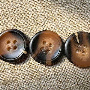 May include: Three brown and black patterned buttons with four holes each.