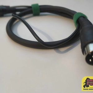 Puede incluir: Cable negro con una brida de cable verde y un conector DIN de 9 pines.
