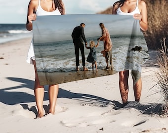 May include: A beach towel with a photo of a family of four standing on a beach. The family is holding hands and smiling. The beach is sandy and the water is blue.
