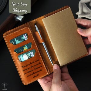 May include: A brown leather notebook cover with a pen, credit card slots, and a notepad. The cover has the text "May your hard work bring you the rewards you deserve. Cheers to more achievements ahead!"