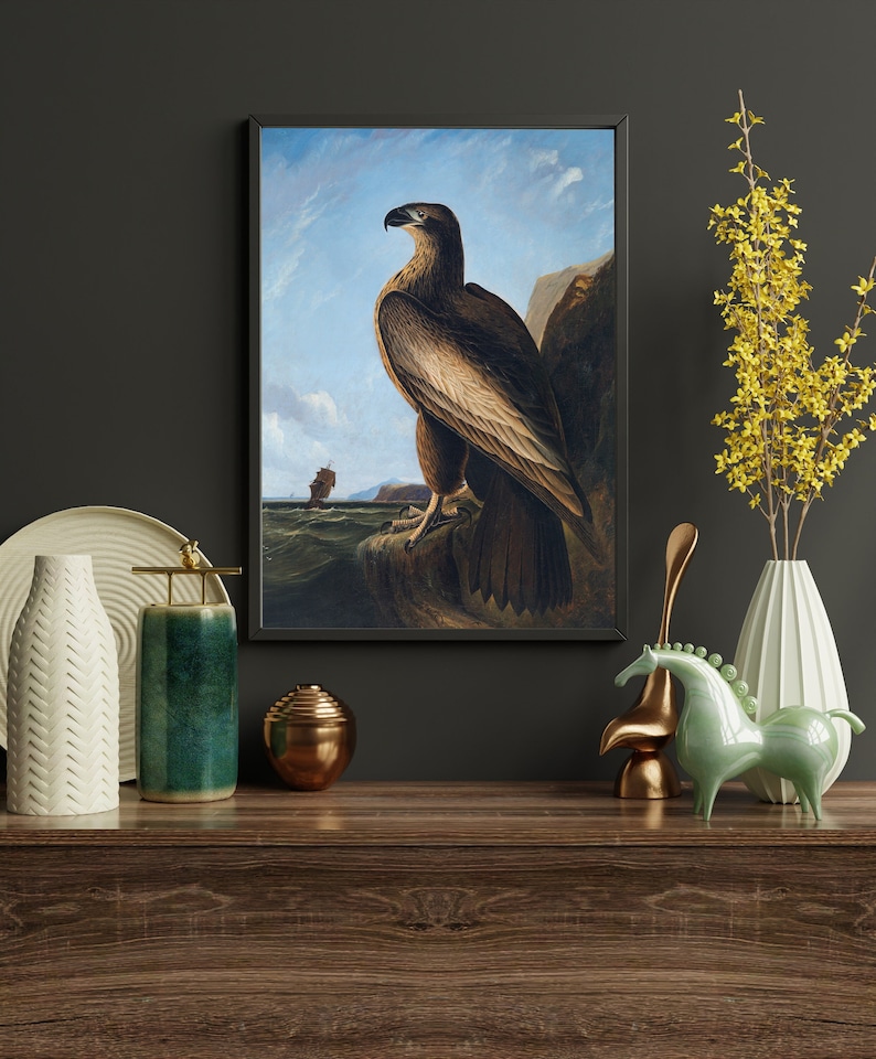 May include: A framed painting of a brown eagle perched on a rock with a ship in the distance. The eagle is looking to the left, and the background is a blue sky with white clouds.
