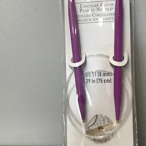 May include: A package of Loops & Threads circular knitting needles. The needles are purple with a clear plastic cord. The package reads "CIRCULAR COLOR PLASTIC NEEDLES" and "US 11 (8 mm) 29 in (75 cm)".
