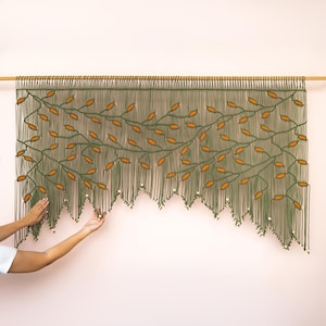 Intricate geometric macrame header transitioning into a sweeping leaf-patterned fringe.