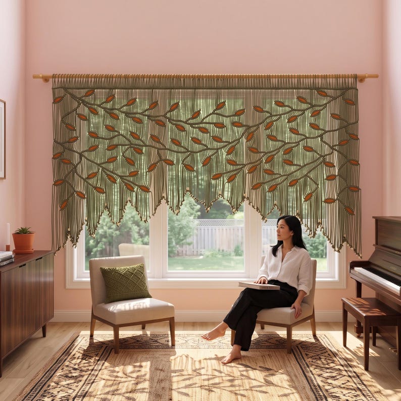 May include: A macrame window valance featuring a green cord design with orange leaf-shaped accents. The valance hangs from a wooden rod and displays a branching vine pattern with a fringed bottom edge, covering the upper portion of a window.