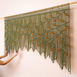 Nature-inspired fiber wall art with an olive green background and falling orange leaf design.