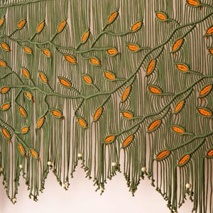 Handcrafted olive macrame tapestry with a multi-layered architectural scalloped fringe.