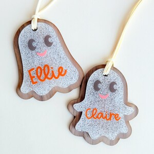 two personalized name tags, each shaped like a ghost with the name "Ellie" and "Claire" written on them.