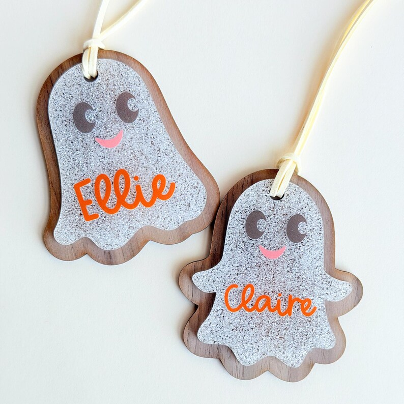 two personalized name tags, each shaped like a ghost with the name "Ellie" and "Claire" written on them.