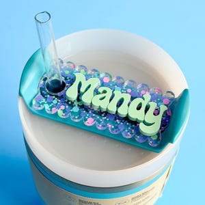 A blue and white container with a clear lid, featuring a decorative label that says "Manay" in a playful font.