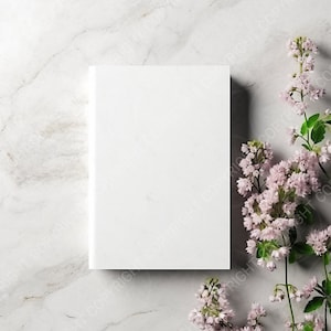 Puede incluir: Una portada de libro blanca en blanco sobre un fondo de mármol con flores rosas en el lado derecho de la imagen.