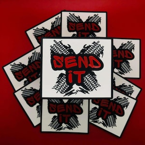 May include: A stack of black and white stickers with the words "Send It" in red letters. The stickers feature a graphic of tire tracks.