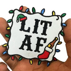 May include: Embroidered patch with the text "LIT AF" in black block letters. The patch features a Christmas stocking, a beer bottle, and a Santa hat. The patch is surrounded by colorful Christmas lights.