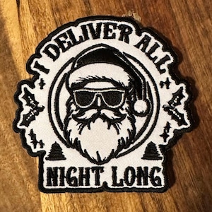 May include: A black and white patch featuring Santa Claus wearing sunglasses and a Santa hat. The text "I DELIVER ALL NIGHT LONG" is printed around the image of Santa. The patch has a white background and a black border.