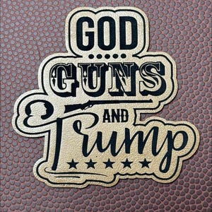 May include: Gold sticker with black text that reads "GOD GUNS AND TRUMP" with five stars below the text.