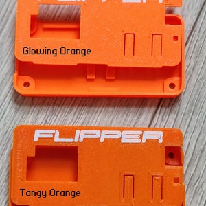 以下が含まれることがあります： 上部に白で「FLIPPER」と印刷されたオレンジ色のプラスチックケースが2つあります。 上部のケースには「輝くオレンジ」とラベル付けされ、下部のケースには「タンジーオレンジ」とラベル付けされています。