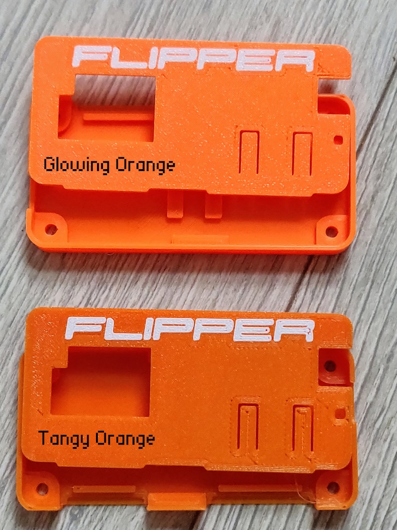 以下が含まれることがあります： 上部に白で「FLIPPER」と印刷されたオレンジ色のプラスチックケースが2つあります。 上部のケースには「輝くオレンジ」とラベル付けされ、下部のケースには「タンジーオレンジ」とラベル付けされています。