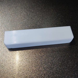 May include: A white rectangular block with a smooth surface. The block has a faint inscription on the top.