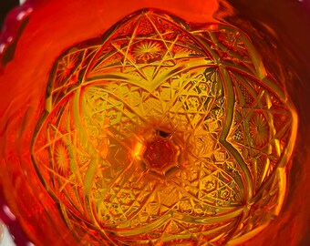 May include: A vintage orange glass bowl with a cut glass design. The bowl has a scalloped rim and a deep, round shape.