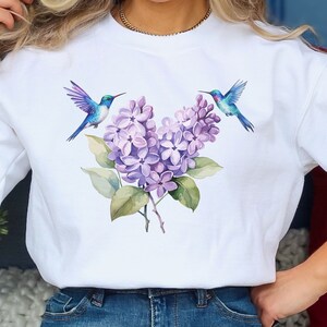 May include: White sweatshirt with a purple lilac flower design and two blue hummingbirds.