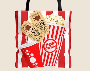May include: A tote bag with black straps featuring a red and white vertical striped background. The design includes two tan cinema tickets, a red soda cup with a white straw, and a red and white striped popcorn bucket labeled POP CORN.