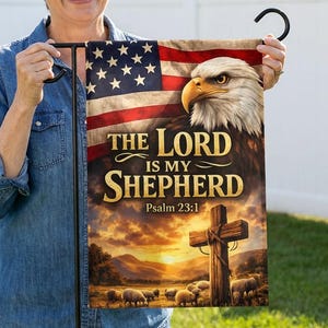 Könnte beinhalten: Eine Gartenflagge mit einem Design der amerikanischen Flagge, einem Adler und dem Text "THE LORD IS MY SHEPHERD Psalm 23:1". Die Flagge wird von einer Person gehalten und hat einen schwarzen Metallbügel.