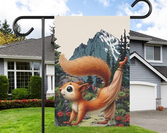 May include: A garden flag featuring a cartoon squirrel doing yoga in front of a mountain range. The squirrel is orange and brown with a white belly and is wearing a brown yoga outfit. The background is a light beige with green trees and a blue mountain range.