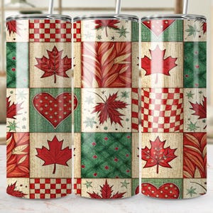 May include: A stainless steel tumbler with a patchwork design featuring red maple leaves, hearts, and checkered patterns on a cream, green, and red background. The tumbler has a silver straw.