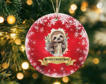 May include: A red and white Christmas ornament with a cute sloth holding onto a branch. The ornament has a gold ribbon and the text "Merry Christmas" on it.