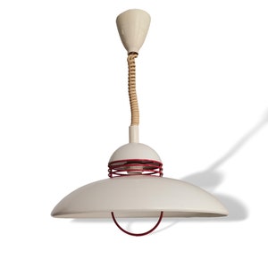 Op de afbeelding: Witte hanglamp met een gevlochten snoer en een rode metalen ring rond de onderkant van de kap.