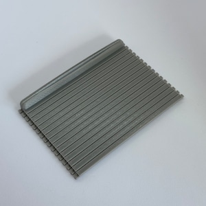 May include: A gray plastic slatted surface with a raised edge on one side. The surface is designed for use as a model railroad or miniature scene building material.