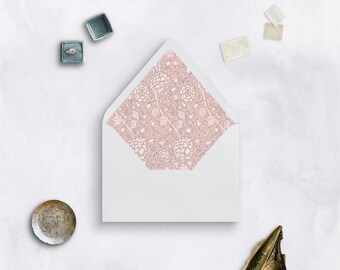 May include: A white envelope with a pink floral pattern lining the inside flap. The envelope is on a white surface.