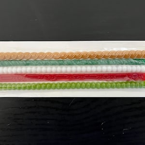 May include: A package of decorative wax sticks in various colors. The sticks have different designs, including a twisted rope, beaded, and patterned styles. Colors include tan, green, white, red, and lime green.