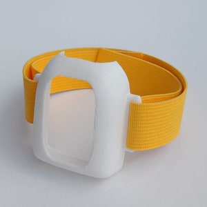 Könnte beinhalten: Weißer 3D-gedruckter Handyhalter mit einem gelben Gummiband.
