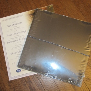 Könnte beinhalten: Eine Packung mit 12x12 Zoll großen Seitenschützern für Scrapbooking. Die Packung ist mit dem Text "Page Protectors", "Protecteurs de page", "Protectores de Páginas" und "Seiten-Schutz" beschriftet.